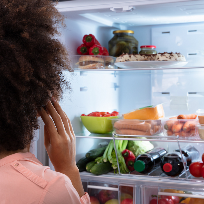 Woman looking at her open, filled fridge